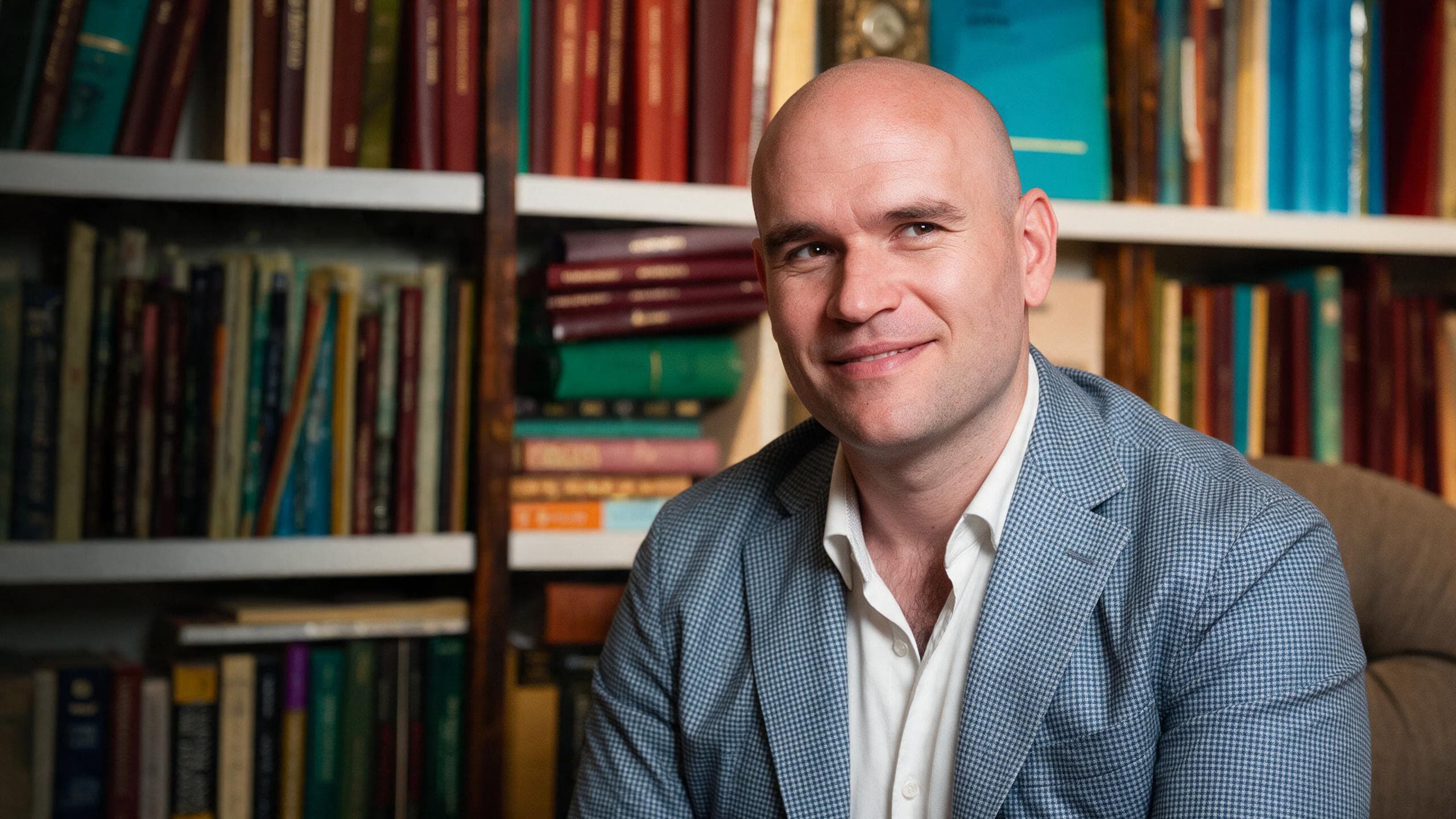 Michael Fabiano seated in front of a wall of bookshelves